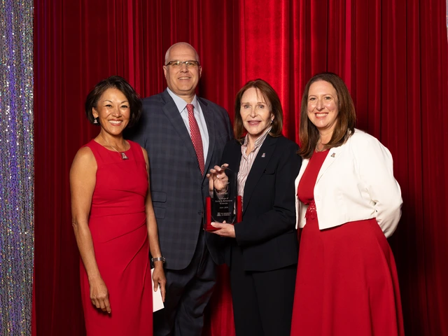 Three women and one man stand together for a photo in a formal setting