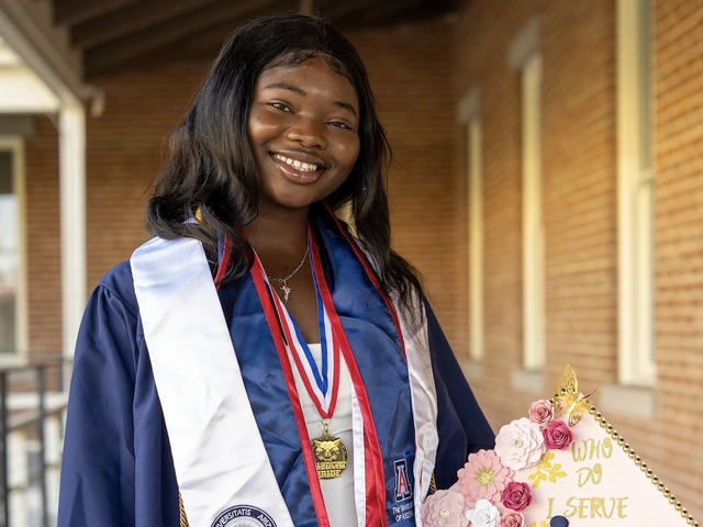 Student stands outside in graduation regalia, holding a graduation cap 