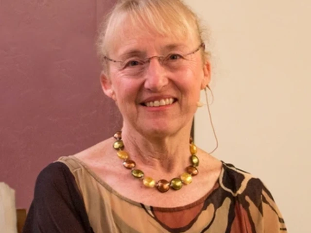 Mary Stiner sits in front of a brown and white wall, smiling