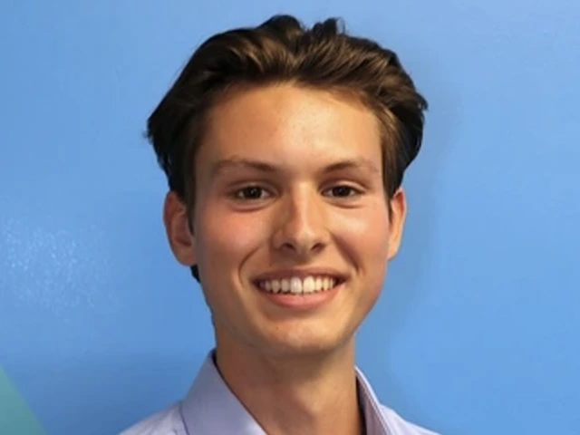 Young man with dark blonde hair and wearing a blue collared shirt smiles against a blue background