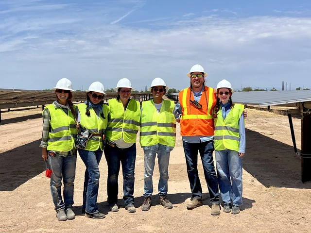 Greg Barron-Gafford and four members of his team, wearing safety vests and hard hats stand outside next to solar panels