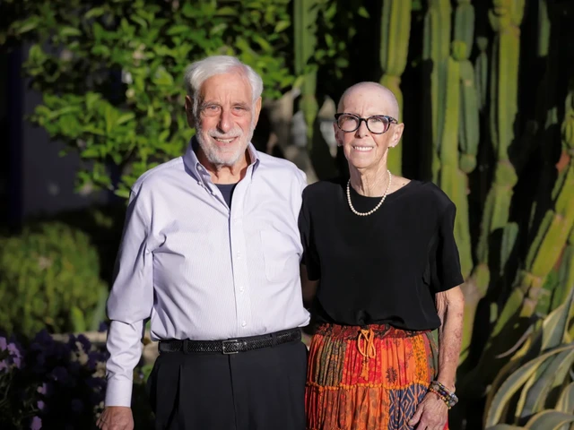 An older man and woman stand outside in front of cacti
