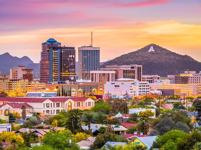 Tucson skyline at sunset, with the city’s buildings silhouetted in warm light and the iconic mountain in the background.