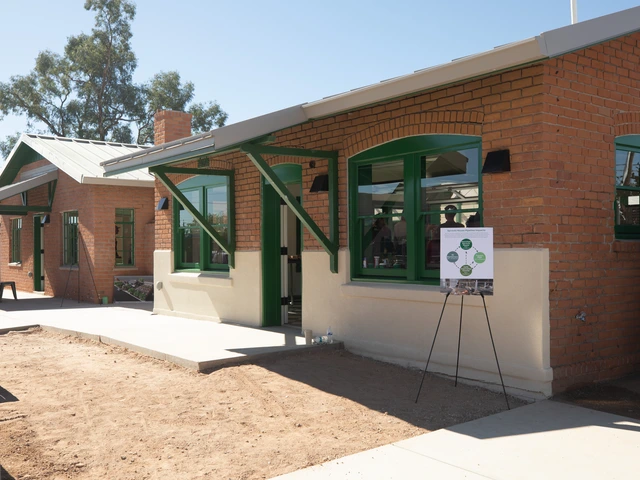 Two renovated brick homes with green trim. There is a sign on an easel and chair and benches set up for guests.