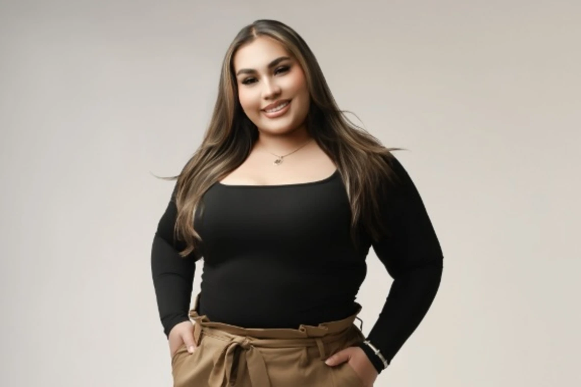 Woman with long brown hair and wearing a black top and brown pants