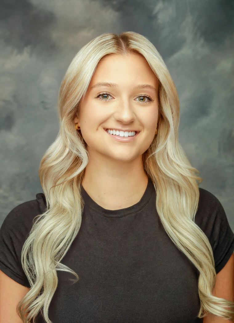 Talia in front of a gray background wearing a blackshirt. 