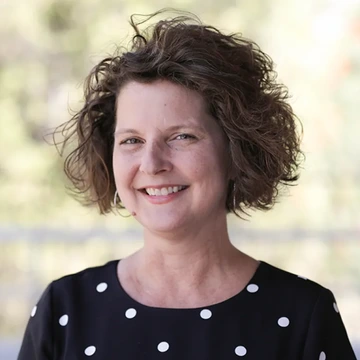 Woman with short brown hair and a black and white shirt smiles