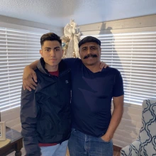 Young man in the right, stands with his father, on the left