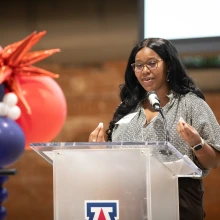Kiara Adams stands behind a podium with a UA logo