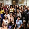A group of young Latin American women scholars and NNI/UA staff posed together in front of a trophy case in a bright indoor space. They smile broadly, wearing casual clothing, as they celebrate their participation in the SUSI Women’s Leadership program