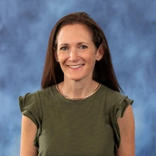 woman with long brown hear and wearing a dark green top
