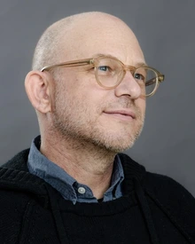 Man wearing gold framed glasses and a black sweater