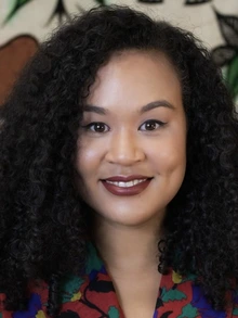 Woman with black hair wearing a multicolored red top