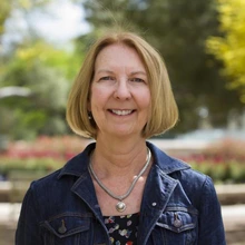 Woman with a short blonde bob and blue shirt stands outside