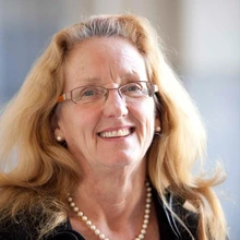 Woman with strawberry blonde hair and glasses, smiling