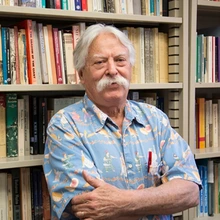 Man with gray hair and mustache and wearing a light blue shirt